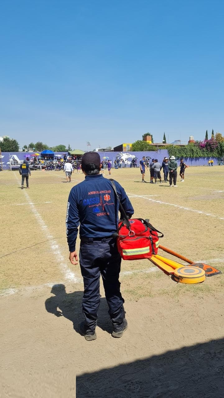 Paramédico de CASSEI trasladando tabla espinal en un campo deportivo