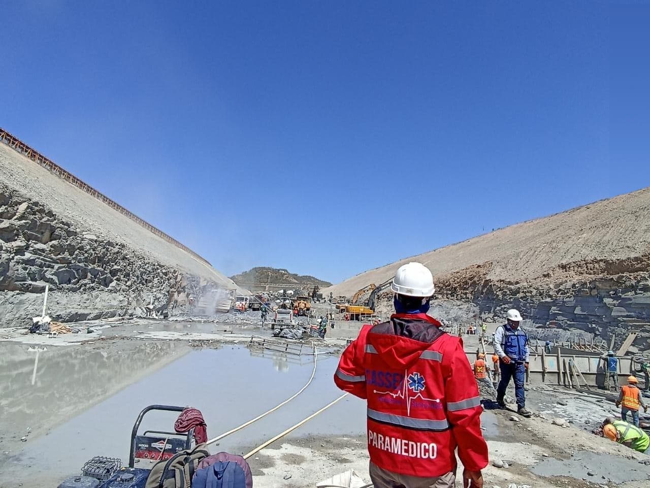 Paramédico de CASSEI con uniforme rojo frente al frente de obra de la Presa Libertad